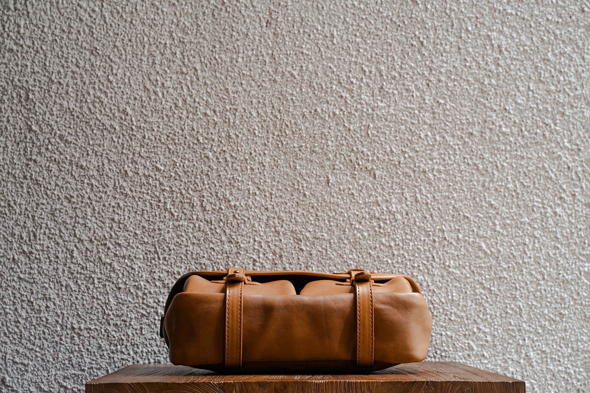 One of our signature design cues, the body straps go all around the bag, providing a load bearing structure for the bag. Keeping with the goal to minimize seams, the sides and bottom are made from one big piece of leather.